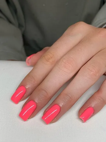 A vibrant, solid coral-pink manicure on perfectly shaped square nails. This is a great example of a simple, bold color making a big impact.