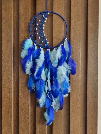 This crescent moon dreamcatcher in shades of royal and sky blue is designed to capture the magic of your dreams. The feather arrangement adds a sense of fullness and movement.