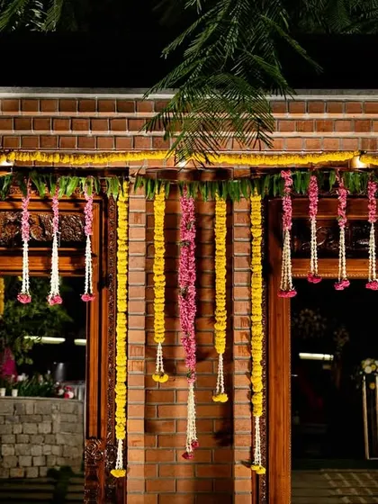 The entrance to a traditional South Indian wedding, adorned with marigold garlands and banana leaves. This sets a welcoming and auspicious tone for the guests as they arrive.