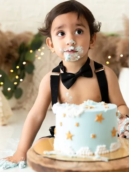 A thoughtful pause amidst the fun of a cake smash, with blue frosting and a star-decorated cake.