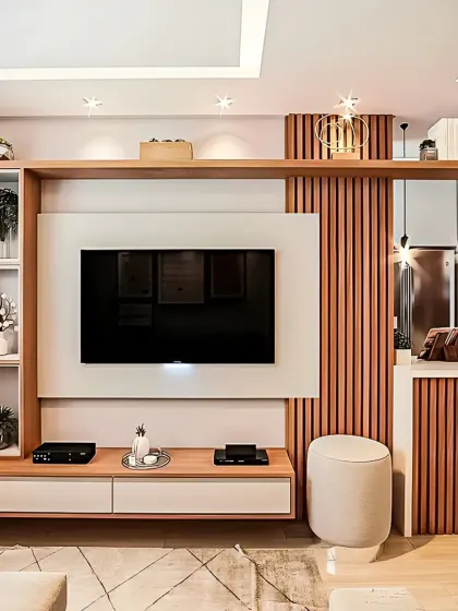 A bright and airy living space centered around a custom TV unit. The design incorporates vertical wood slats, open shelving for decor, and a cozy pouf, blending functionality with modern aesthetics.