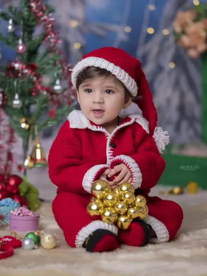 A baby Santa sitting amidst a pile of golden ornaments. This close-up shot captures the wonder and magic of a baby's first Christmas.