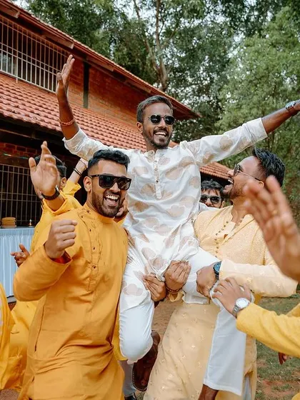 The groom is lifted up by his friends in celebration during the Haldi festivities.