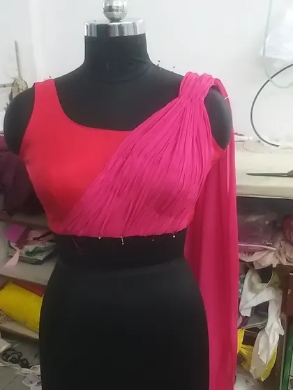 A work-in-progress shot of a custom blouse. This design features a unique draped element across the bodice, created with carefully pleated georgette fabric. We pin and stitch everything on the mannequin to ensure a perfect fit.
