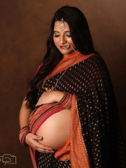 A stunning bare-bump portrait in a black and orange saree. The traditional jewelry completes the look.
