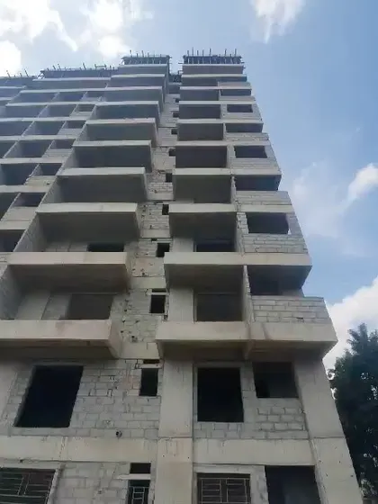 A duplicate image looking up at the unfinished facade, illustrating the building's verticality.