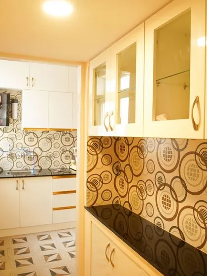 This kitchen renovation features a bold, circular-patterned tile for both the floor and backsplash, creating a cohesive and high-impact design. The white cabinets and gold-tone handles add a touch of retro glamour.