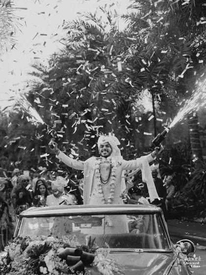 The groom's celebratory exit in a vintage car, showered with confetti, a perfect black and white shot full of energy and style.