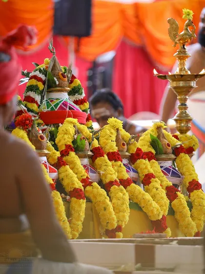 A close up of the decorated kalashas (pots) for the Rishi Homa, adorned with marigold garlands. These pots represent abundance and the divine presence.