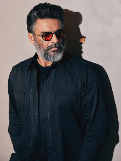 A close-up on the face, where the red glasses provide a striking pop of color against the all-black outfit.