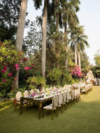 A view of the event space, showing how the long table setup integrates into the larger garden environment. I ensure the decor enhances the venue, creating a cohesive and immersive experience for all attendees.