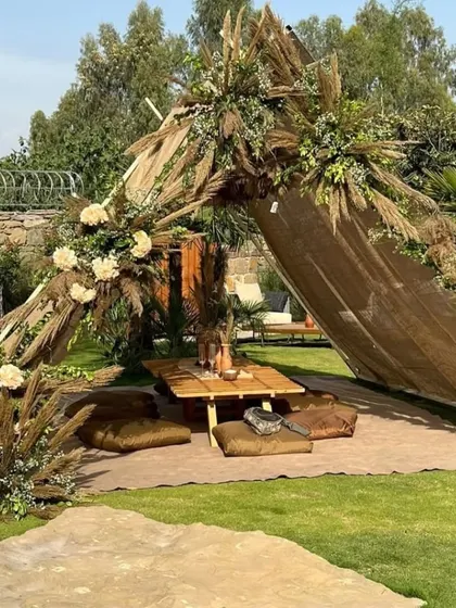 We created this serene boho-chic picnic setup for an outdoor baby shower. It features a draped canopy, low wooden seating with comfortable floor cushions, and arrangements of pampas grass and dried florals for a natural, earthy aesthetic.