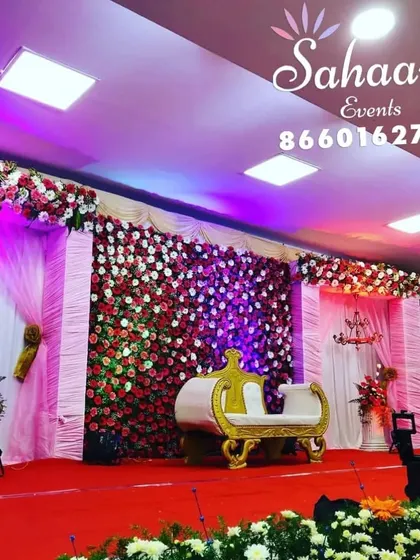 A lavish reception stage with a full wall of red and white roses. The dramatic floral backdrop is paired with elegant drapery and a classic golden-white settee for a truly grand statement.
