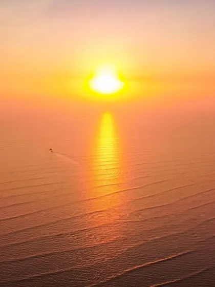 A drone shot of the sunset over the sea in Alibag, where the sun's reflection on the water looks like a lightsaber.