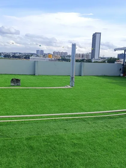 A wide view of the newly installed turf, showing how it covers the area seamlessly. The pipes and utility posts are neatly integrated into the new green landscape.