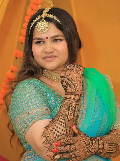 A beautiful portrait of a bride on her mehendi day, adorned with intricate henna. The design complements her traditional attire perfectly.