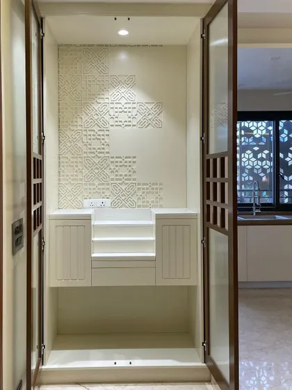 With the doors open, the serene interior of the mandir is revealed. It features a custom CNC-carved Corian backdrop, tiered platforms for idols, and integrated storage, all illuminated by soft overhead lighting.