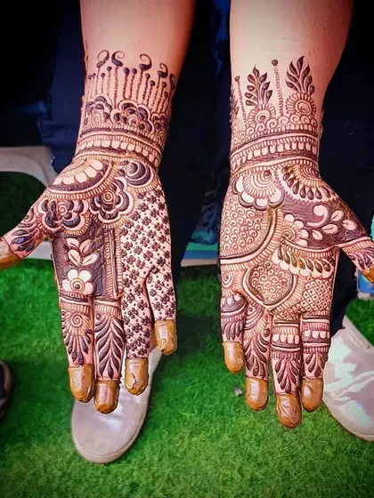 A rich and dense bridal mehandi design with a variety of patterns, including florals, paisleys, and checks, covering the entire palm.
