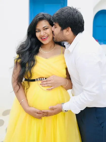 A sweet and candid moment captured during a couple's maternity shoot. The vibrant yellow of her tulle gown pops beautifully against his simple white shirt and dark trousers, a classic combination for a bright and happy theme.