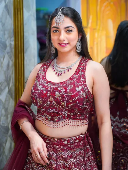 A close-up of the maroon lehenga look, showing off the beautiful jewelry and the intricate work on the blouse.
