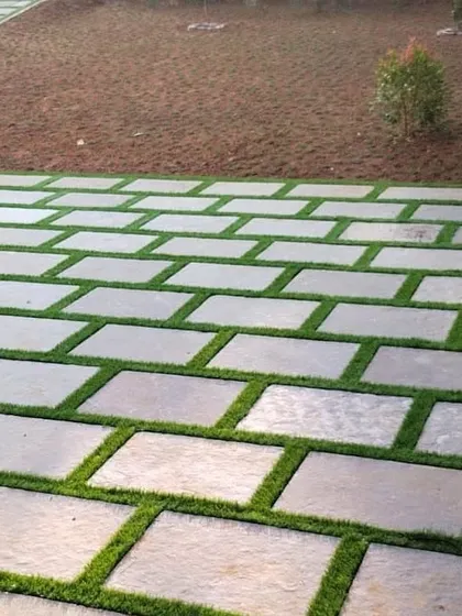 The initial stages of a paver and grass lawn installation. The ground is being prepared, and the pavers are laid out before the grass is planted, showing the methodical approach we take to hardscaping.
