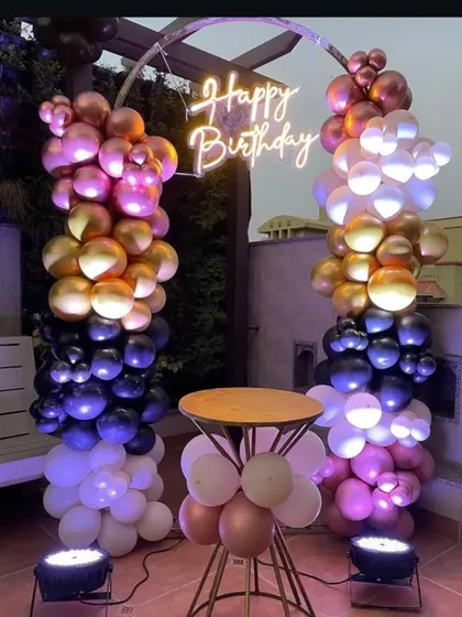 A unique two-pillar balloon arch on a rooftop, creating a colorful and modern frame for a birthday celebration.