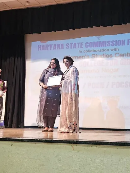 Receiving a certificate on stage at D.A.V. College for Girls, Yamuna Nagar, after speaking at an awareness program on Legal, POSH, and POCSO issues.