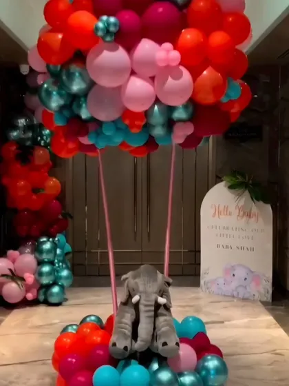 A creative hot air balloon sculpture made of balloons with a plush elephant in the basket, serving as a stunning entrance piece.