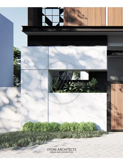 A close-up detail of the Manjulamma residence facade, showing a mix of white marble, wood, and a cut-out that reveals a small green space within.