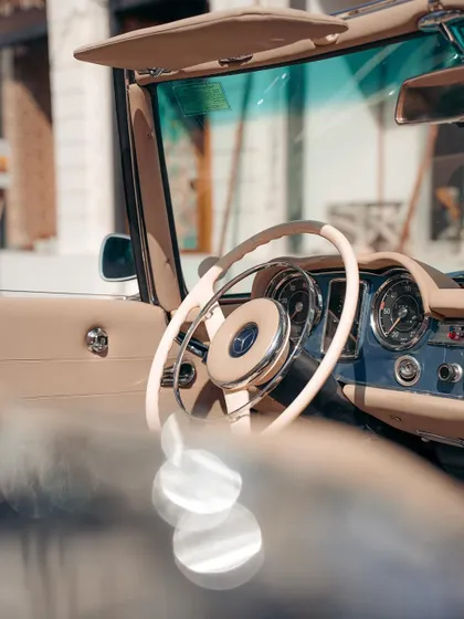 The interior of a classic Mercedes, focusing on the elegant steering wheel and dashboard. This shot captures the craftsmanship and aesthetic of a different time.