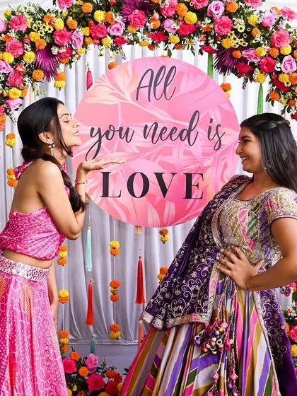 "All you need is LOVE." A fun and colorful circular photo arch, perfect for capturing playful moments during a mehendi function.