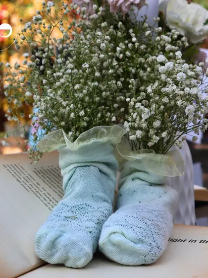 A creative centerpiece using baby socks as a vase for baby's breath, placed on an open book to tie into the literary theme.
