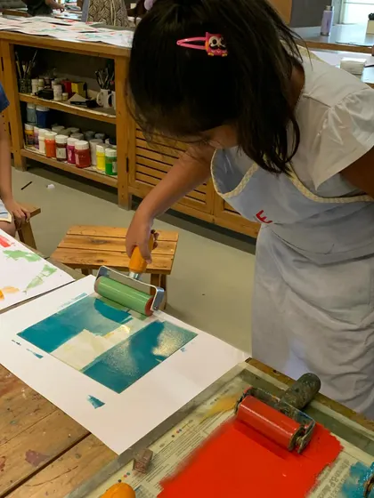 A young artist carefully applies a layer of ink to her printing block. This hands-on part of the printmaking process is where students learn about color mixing and how to get an even coat for a perfect print.