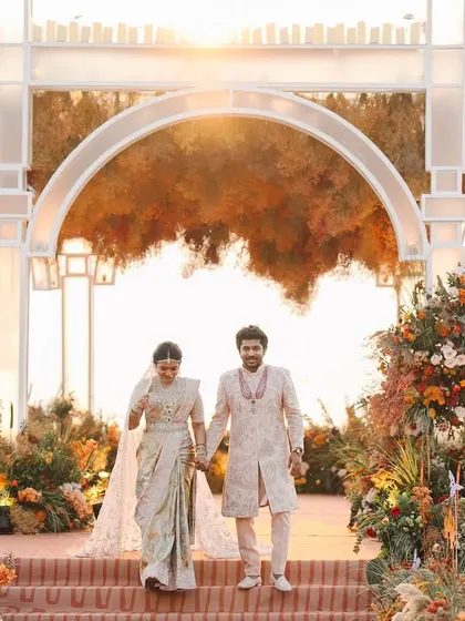 The couple's grand entrance at their sunset wedding in Goa. The mandap, with its warm, autumnal florals, perfectly frames them against the golden hour sky.
