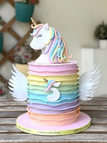A perfect pastel rainbow unicorn cake with beautiful wings! The ruffled layers of color and the sweet unicorn topper make this a dreamy and magical choice for a birthday celebration.