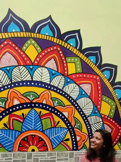 A photo of me with the vibrant mandala mural. This type of spiritual art is perfect for creating a focal point in a room that promotes peace and positive energy.