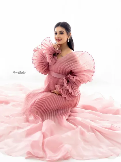 A full-length portrait showcasing the beautiful design and flow of this soft pink pleated gown.