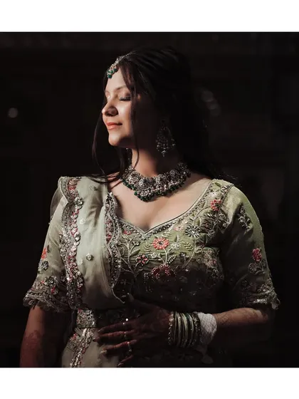 A serene portrait of bride Ekta during her Mehndi ceremony, with soft light highlighting her gentle smile and the intricate embroidery of her outfit.