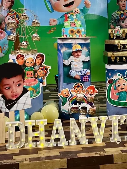 A wide shot of a Cocomelon theme, showcasing how we use character cutouts, personalized photo displays, and light-up letters to create a rich and visually engaging environment for a first birthday.