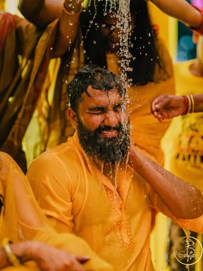 A close-up shot capturing the groom's reaction during the playful water rituals of the Haldi ceremony.