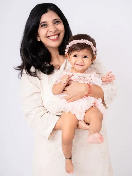 A classic mother and daughter portrait. The simple background and coordinated outfits keep the focus on their happy faces and the connection between them.