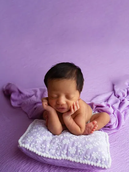 Another variation of the safe 'froggy pose', this time with the baby resting their head on a small pillow. This pose requires specialized training to execute safely.