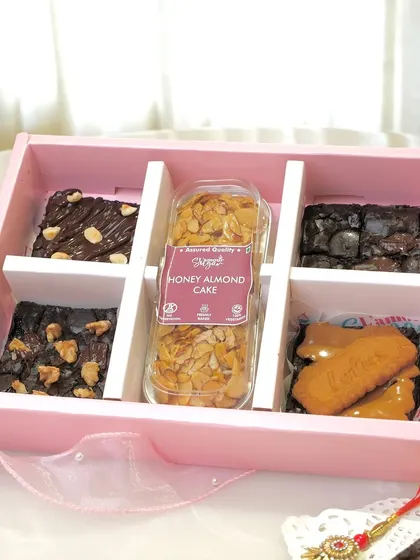 A look inside our iconic brownie and tea cake box, a crowd favorite for over six years. This classic hamper contains four assorted fudgy brownies and a loaf of our comforting honey almond tea cake.
