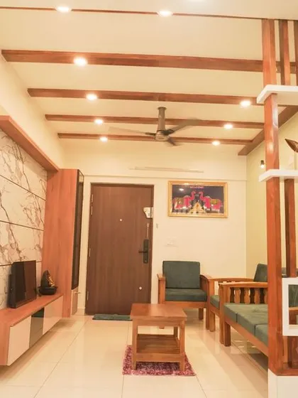 A traditional living room with wooden rafters on the ceiling and a matching wooden partition. The space is designed to feel warm, inviting, and connected.