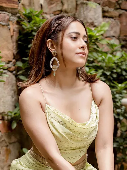 A close-up of Nushrratt in this lime green ensemble, highlighting the intricate jewelry and braided hairstyle that complete the look.