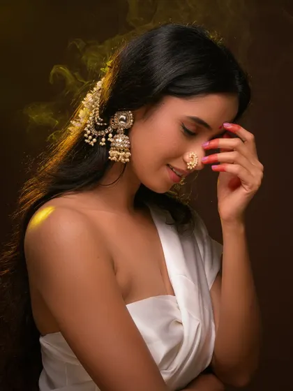 A beautiful and serene ethnic portrait. The model's traditional jewelry and gentle expression are highlighted by warm, soft lighting.
