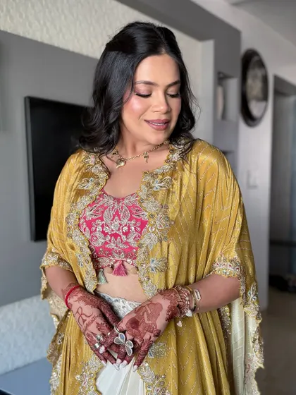 A close-up of the client showing her henna-adorned hands and soft, glowing makeup.