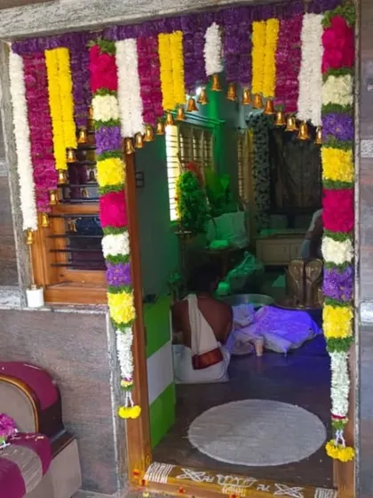 A multi-colored floral entrance decoration, with a person performing rituals inside. My decor sets the perfect stage for your family's traditions.
