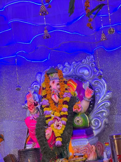Another close-up of the beautifully adorned Ganpati idol, with a serene blue background lit by fairy lights.
