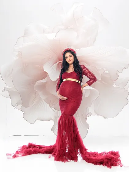 A powerful solo portrait against a giant white paper flower. The bold red lace gown and confident pose create a high-fashion, statement image.